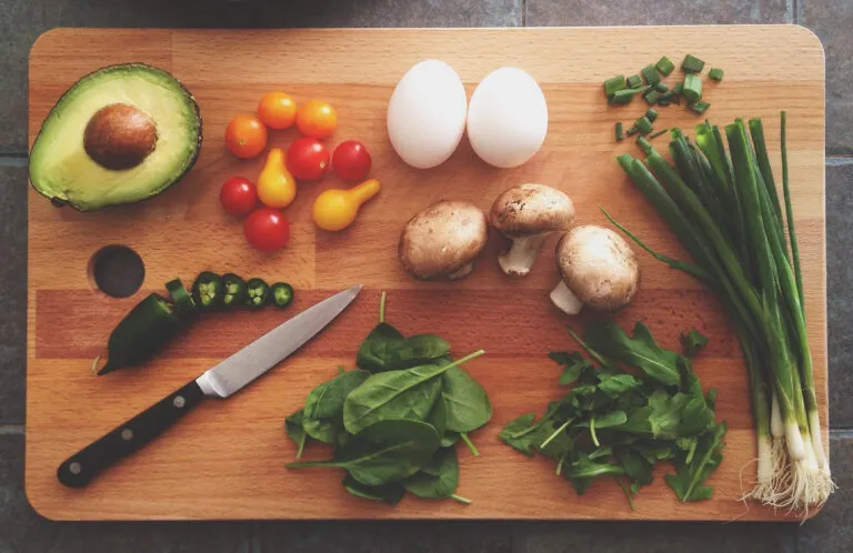 Avokado, svamp, ägg och grönsaker på skärbräda – matbehandling
